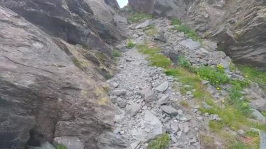 İtalya 'daki Graian Alpleri' nde Passo delle Mangioire yakınlarında kırmızı-beyaz iz taşıyan kayalar arasında dar yürüyüş patikalarında yürüyoruz.