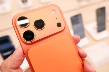 Hand holding a new iPhone 17 Pro Max in an Apple Store Central World. New Color Cosmic Orange. Copy Space