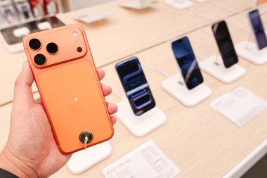 Hand holding a new iPhone 17 Pro Max in an Apple Store Central World. New Color Cosmic Orange. Copy Space