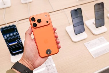 Hand holding a new iPhone 17 Pro Max in an Apple Store Central World. New Color Cosmic Orange. Copy Space