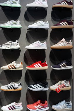 Adidas 'ın ayakkabıları mağazada sergileniyor. Mağazanın içinde bir ayakkabı duvarı manzarası. Modern yeni şık koşu ayakkabıları..