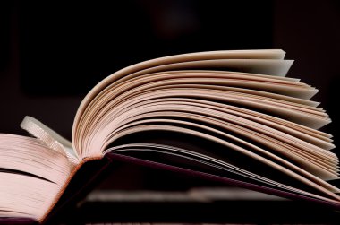 Ahşap masa ile koyu arka plan üzerine açık kitap.
