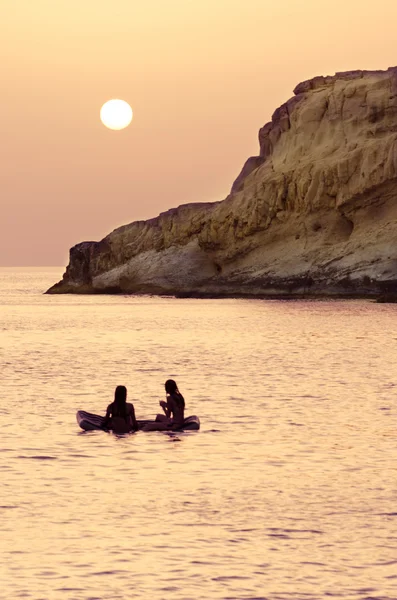 Duas meninas relaxam em seu inflável, apreciando o por do sol . — Fotografia de Stock