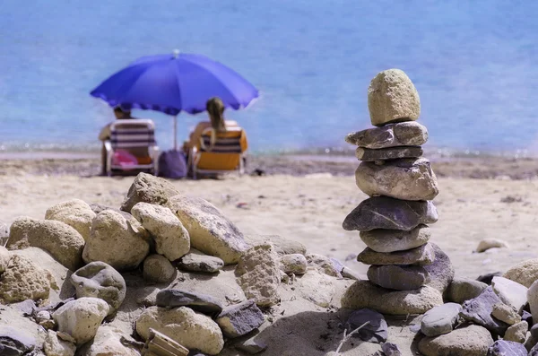 Casal com umprella na praia com seixos torre Zen — Fotografia de Stock