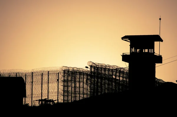 Silhouette of barbed wires and watchtower of prison