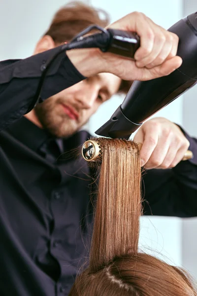 Peluquero seca el cabello con el secador de pelo de joven, hermosa chica en un salón de belleza — Foto de Stock