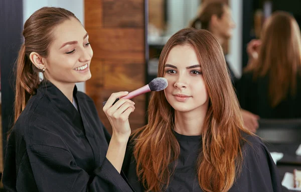 young, beautiful girl put on make-up in a beauty salon