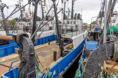 Yüksek açılı manzara, iki balıkçı teknesi arasındaki dar alana bakıyor. Karmaşık güverteleri, ipleri ve geminin üst yapısını vurguluyorlar..