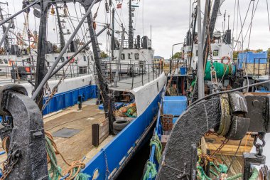 Birebir aynı mavi ve beyaz balıkçı teknelerinin yan yana kenetlenmiş yüksek açılı görüntüsü, kompleks donanım ve balıkçı teçhizatı içeriyor..