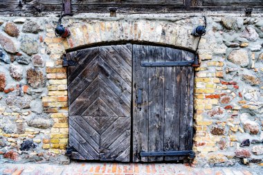 Küçük bir sandalyede oturan bir adam beton bir iskelede çubukla balık tutuyor ya da hazırlanıyor. Büyük, gri bir savaş gemisinin ve uzun bir iskele vincinin tam önünde..