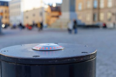 Arka planda bulanık figürlerle tarihi bir kaldırım taşı meydanında duran küçük turuncu / kırmızı ışıkların yer aldığı gümüş renkli, aydınlık bir bölümle koyu renkli, ağır trafik kordonunun yakın plan çekimi..