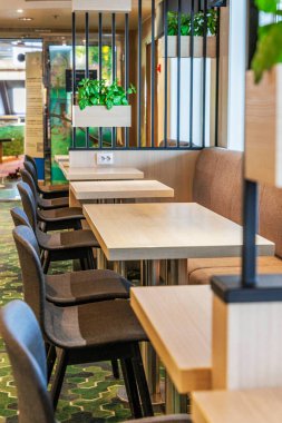 Bir feribotta, seyahat ve konukseverlik kavramları için ideal, modern, düzenli bir kafe veya oturma alanında bir dizi açık tahta masa ve koyu gri sandalyeler..