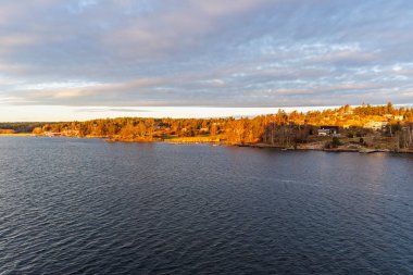 Karanlık suların ötesinden İskandinav takımadalarının yoğun ormanlık ve meskun kıyı şeridine doğru geniş bir görüş açısı var..