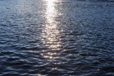 Koyu mavi suyun aşırı yakın çekimi, çok ince yansımaları olan, küçük, düzensiz dalgalanmalar ve dokuların karmaşık bir soyut modelini gösteriyor..