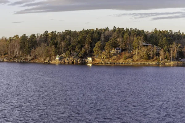 Ormanlık, kayalık İskandinav kıyı şeridi gözlerden uzak bir kulübe ve küçük, farklı bir navigasyon ışığı veya deniz feneri..
