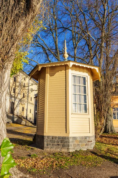 Stockholm 'de açık mavi bir gökyüzünün altında ağaçlarla çevrili, taş tabanı ve penceresi olan tuhaf, küçük, sarı ahşap bir pavyon..