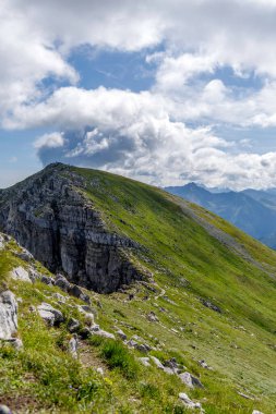 Bir grup insan bulutlu bir gökyüzünün altındaki dik yeşil bir dağ sırtında yürüyor. Tatras 'ta macera, sağlıklı yaşam tarzı ve yaz turizmi kavramı.