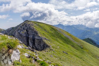 Bir grup insan bulutlu bir gökyüzünün altındaki dik yeşil bir dağ sırtında yürüyor. Tatras 'ta macera, sağlıklı yaşam tarzı ve yaz turizmi kavramı.
