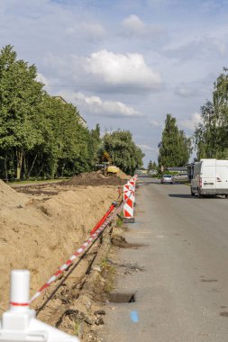 Kum yığınları, kazıcı ve trafik engelleriyle sokak yenileme işlemi. Altyapı geliştirme ve inşaat mühendisliği için iş kavramı.