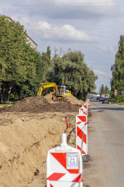 Turuncu kazıcı bir inşaat alanındaki bir kamyona toprak taşıyor. İş dünyası, inşaat mühendisliği ve ağır sanayi temaları için ideal.