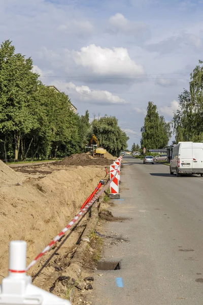 Kum yığınları, kazıcı ve trafik engelleriyle sokak yenileme işlemi. Altyapı geliştirme ve inşaat mühendisliği için iş kavramı.