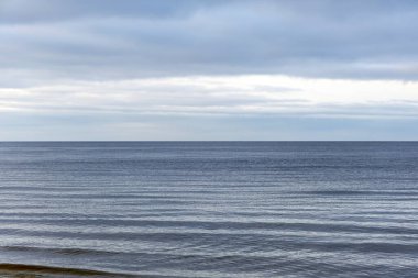 Düz bir ufuk, yumuşak su dalgaları ve buzlu plaj detaylarının yer aldığı minimalist bir kış sahnesi. Sakin, doğal ve çevresel kavramlar için mükemmel..