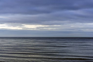 Düz bir ufuk, yumuşak su dalgaları ve buzlu plaj detaylarının yer aldığı minimalist bir kış sahnesi. Sakin, doğal ve çevresel kavramlar için mükemmel..