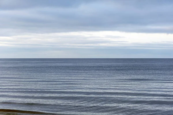 Düz bir ufuk, yumuşak su dalgaları ve buzlu plaj detaylarının yer aldığı minimalist bir kış sahnesi. Sakin, doğal ve çevresel kavramlar için mükemmel..