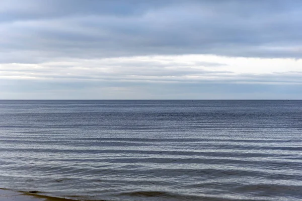 Düz bir ufuk, yumuşak su dalgaları ve buzlu plaj detaylarının yer aldığı minimalist bir kış sahnesi. Sakin, doğal ve çevresel kavramlar için mükemmel..