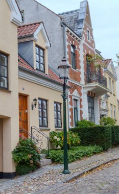 Danimarka 'da Viborg: Tuğla ve alçı cepheleri, yeşil çalılar ve klasik bir sokak lambasının yer aldığı tarihi evlerle dolu sessiz bir kaldırım taşı caddesi.