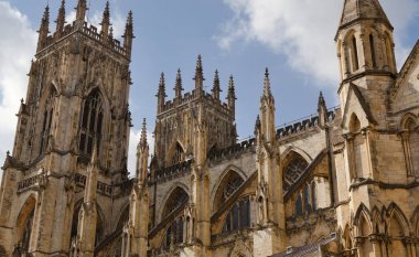 York Minster 'ın detaylı manzarası, gökyüzünün altında kuleleri, kuleleri ve kavisli pencereleri olan Gotik bir katedral..