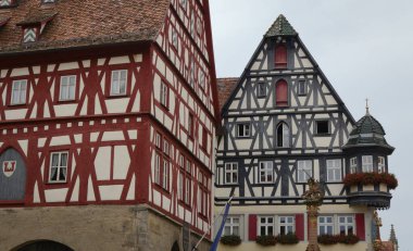 Rothenburg 'da klasik Alman mimarisi sergilenen, bulutlu gökyüzü altında sarp çatıları ve dekoratif kirişleri olan iki geleneksel yarı keresteli ev..