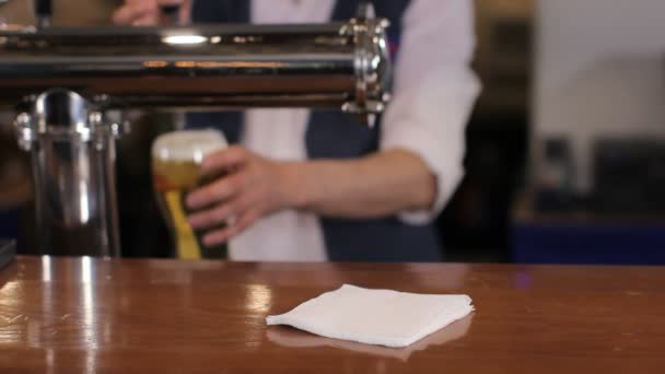 Bartender pouring glass of draft beer, putting it on the bar counter and leaving. Medium shot — Stock Video