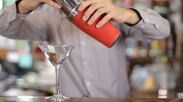 Barman giet coctail van shaker in een glas. Middellange schot — Stockvideo