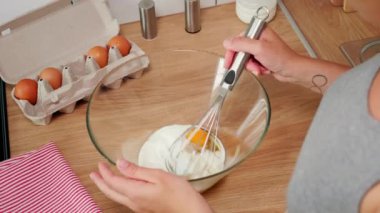 Kız çırpıcıyla bir yumurtayı elle çırpıyor.