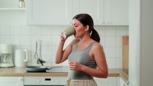 一个女孩站在厨房里，用杯子喝水. — 图库视频影像