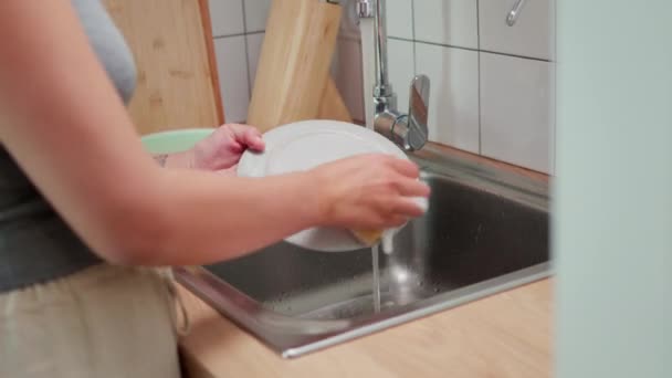 La fille lave soigneusement la plaque sous l'eau avec un gant de toilette — Video