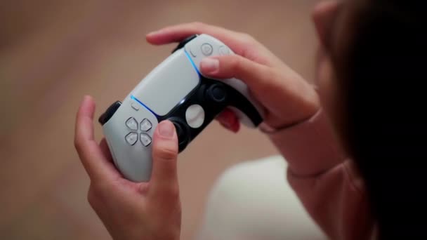 Flickan trycker aktivt på knapparna på den trådlösa joysticken när du spelar konsolerna.Närbild, ram ovanifrån — Stockvideo