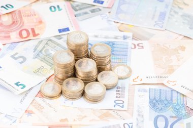 Pile of coins on a layer of bank notes zoomed out