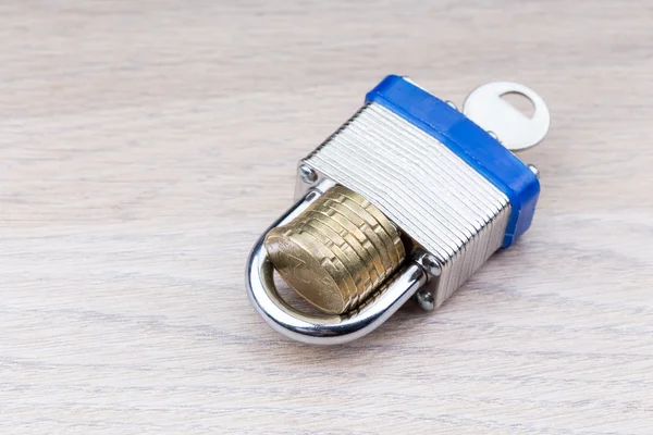 Padlock holding a stack of coins on a table