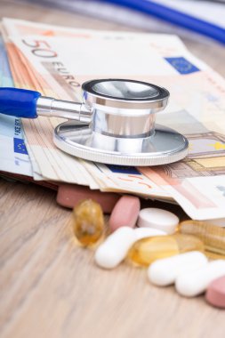 Bir stetoskop ile bazı haplar ve banka notları, yakın çekim