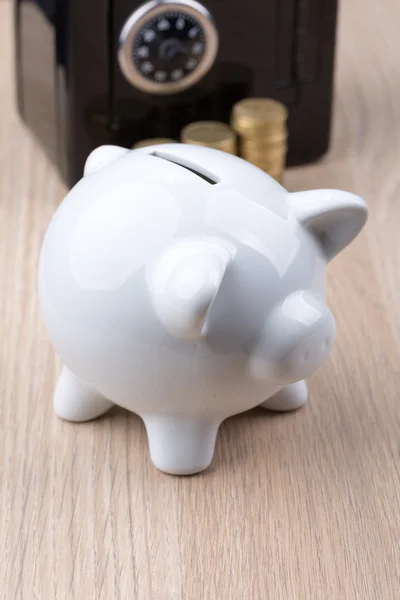 White piggy bank with black metal coin bank in background: a concept for either withdrawing or depositing money