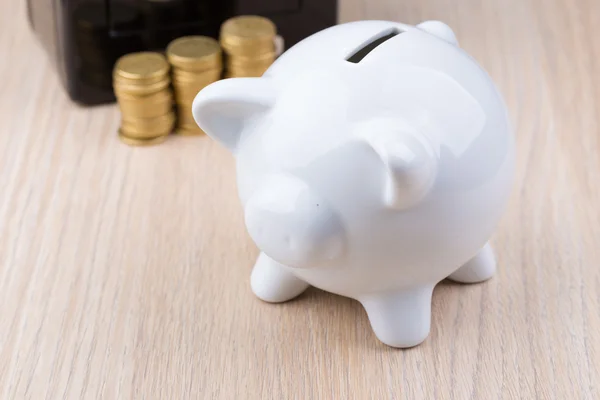 White piggy bank with black metal coin bank in background: a concept for either withdrawing or depositing money