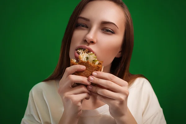 Vackra unga äter en smörgås rolig kvinna hamburgare — Stockfoto