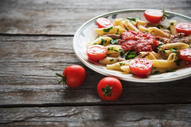 Penne makarna domates soslu tavuk, domates maydanoz dekore edilmiş 