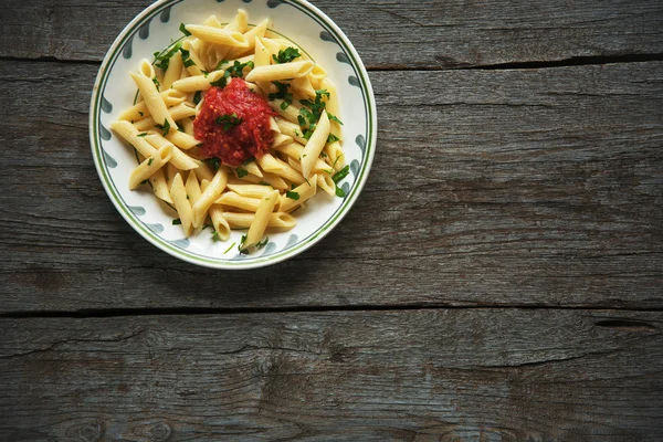 Domates soslu makarna, ahşap arka planda maydanozla süslenmiş domates.