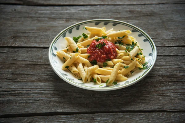 Domates soslu makarna, ahşap arka planda maydanozla süslenmiş domates.