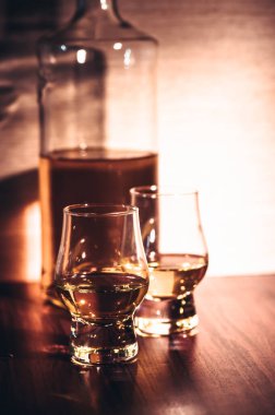 Kırsal ahşap arka planda seçici odaklanmış viski bardakları, barda tezgahta içki içerken viski ya da ahşap masada buz küpleriyle viski içmek..