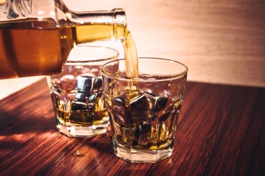 Kırsal ahşap arka planda seçici odaklanmış viski bardakları, barda tezgahta içki içerken viski ya da ahşap masada buz küpleriyle viski içmek..