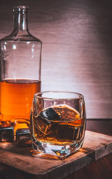 Selective focus glasses of whiskey on rustic wood background, Alcohol drink whiskey or bourbon with ice cubes on wood table together while at bar counter in the pub.